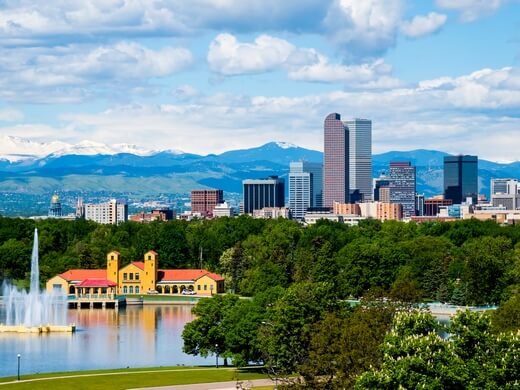 Iconic view of Downtown Denver skyline and mountains from City Park lake.