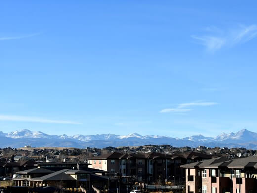 Distant view of Denver residential neighborhoods against the Rocky Mountains.